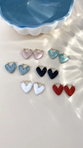 Dettaglio di orecchini a cuore in sei finiture colorate effetto marmo lucido