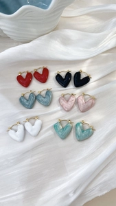 Dettaglio di sei paia di orecchini a forma di cuore in colori vari su sfondo di seta