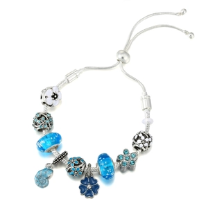 Detail eines Bettelarmbands mit blauen Glasperlen und silbernem Muschelanhänger