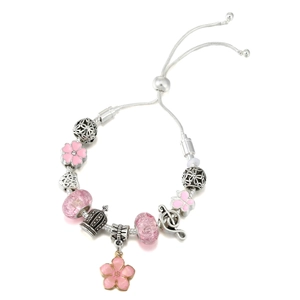 Detail eines rosa Charm-Armbands mit Emaille-Blumenanhängern und Musiknoten-Perlen