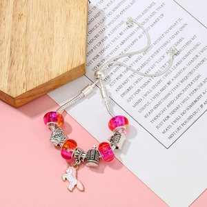 Details des silbernen Einhorn-Armbands mit rosa Perlen und Schlossanhängern auf rosa Hintergrund
