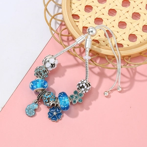 Detail eines verstellbaren Schlangenkettenarmbands mit blauen Perlen und Muschelanhängern