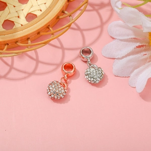 Rose gold and silver heart charms with pavé crystals on a pink background