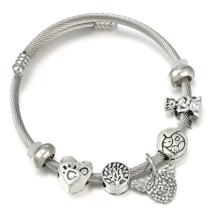 Détail du bracelet à perles avec arbre de vie et breloques cœur sur fond blanc