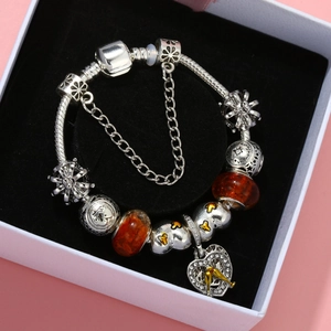 Aquarius zodiac charm bracelet with orange beads on black velvet jewelry box