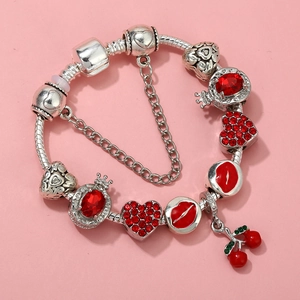 Close-up of silver snake chain bracelet featuring red heart charms and cherry pendant