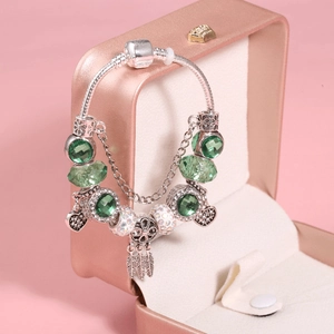 Silver snake chain bracelet with green beads and heart dreamcatcher charms in a gift box