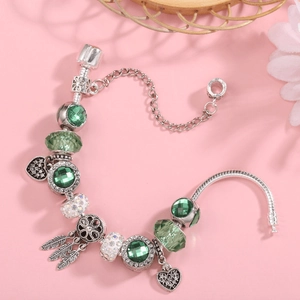 Silver snake chain bracelet with emerald green faceted beads and feather charms