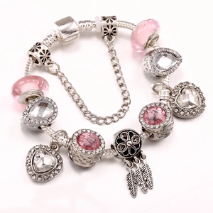 Pink charm bracelet with dreamcatcher feather pendant and crystals on white background