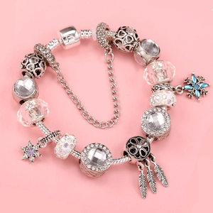 Silver bracelet with crystal beads, snowflake charm, and feather dangles on pink background