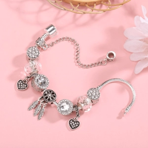 Silver snake chain charm bracelet with heart and feather pendants on pink background
