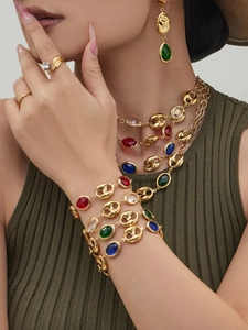 Detail of vintage gold jewelry set featuring colorful oval gemstones and link chain design