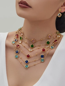 Detailaufnahme der mehrlagigen Goldkette mit bunten quadratischen Glassteinen und Ohrringen