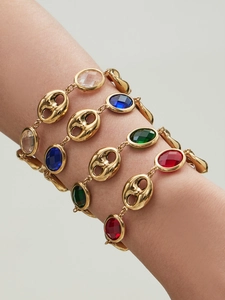 Detail of four gold bracelets with transparent, blue, green, and red glass stones