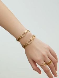 Détail de bracelets gourmette en acier doré 18 carats et bagues en zircon sur la main