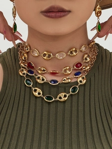 Close-up of gold layered necklace with vibrant faceted gemstones and pig nose links