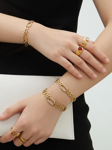 Détail de bracelets à maillons plaqués or 18k avec zircons et bagues sur un mannequin