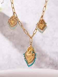 Close-up of gold chunky chain necklace with turquoise beads and sacred heart pendants