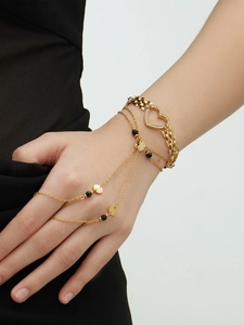 Macro view of 18k gold plated slave bracelet with zircon heart and black bead accents