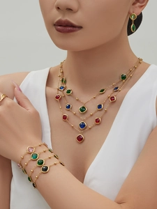 Detail of layered gold necklace set with colorful geometric square glass stones on a model