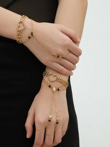 Detail view of heart-shaped gold-plated bracelet and hand chain set with zircon stones