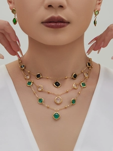 Detailed view of layered 18k gold plated necklace and earrings with square cut gemstones