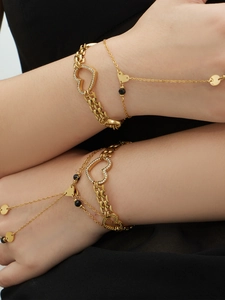 Detail of layered gold-plated bracelets featuring zircon heart charms and natural stone beads