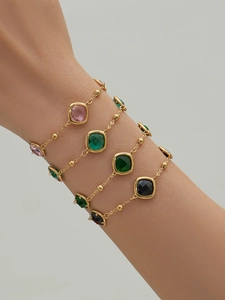 Macro shot of 18k gold plated bracelets set with pink, green and black square gemstones