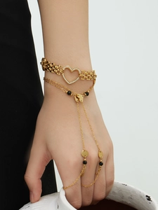 Detailed shot of 18k gold plated heart bracelet and finger chain set with black beads