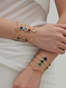 Macro shot of 18k gold plated bracelets with vibrant square cut faceted gemstones on wrist