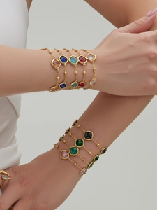 Macro shot of 18k gold plated bracelets with multi-color square gemstones on wrist