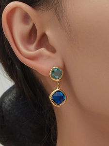 Detail of square-cut light and dark blue stone earrings with gold-plated finish