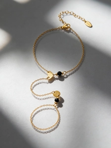 Macro detail of 18k gold plated stainless steel heart finger bracelet with black beads