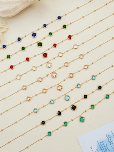 Macro view of gold chain necklaces with colorful square gemstones and beaded details