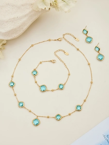 Macro detail of gold-plated stainless steel jewelry set with square blue glass stones
