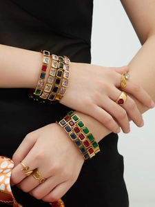 Dettaglio di bracciali in acciaio inossidabile placcati oro 18k con pietre di vetro quadrate