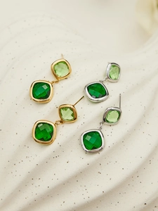 Detail view of 18k gold and silver plated earrings with square cut green glass stones