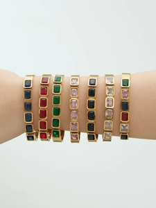 Close-up of gold-plated stainless steel bangles set with colorful rectangular stones