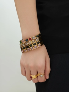 Dettaglio di bracciali e anelli placcati oro con pietre rettangolari colorate