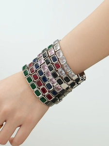 Dettaglio di bracciali in acciaio placcato oro 18k con pietre colorate dal taglio smeraldo
