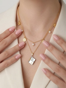 Detail of double-layer gold necklace with pearls and My Little Angel book pendant
