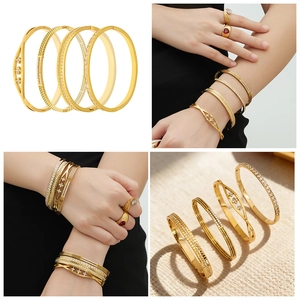Detail van vier 18k goud vergulde roestvrijstalen armbanden met ingelegde zirkonia stenen