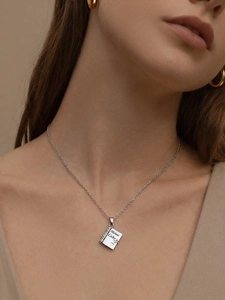 Close-up of model wearing silver book locket necklace with Meine Liebe engraving