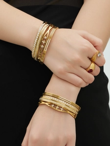 Detailopname van gestapelde 18k vergulde armbanden en ringen met zirkoon op de pols