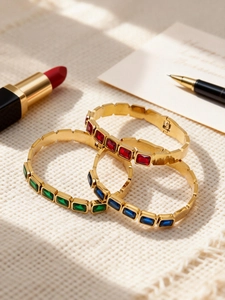 Dettaglio di bracciali in acciaio inossidabile placcato oro 18k con pietre di vetro colorate