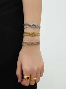 Dettaglio di bracciali a nodo in acciaio inossidabile in oro, argento e bicolore