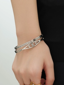 Detail van een zilveren meerlaagse zirkonia-armband met bloemmotieven om de pols