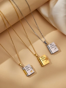 Detailed view of three openable book necklaces with My Little Star engraving on beige fabric