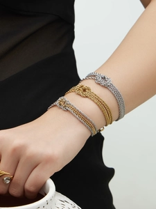Dettaglio di bracciali a catena bicolore con nodo sovrapposti in oro e argento