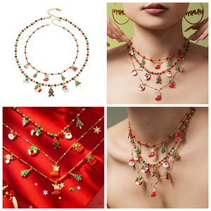 Detail van kerstboom en Kerstman hangers op 18k vergulde ketting met rode kralen